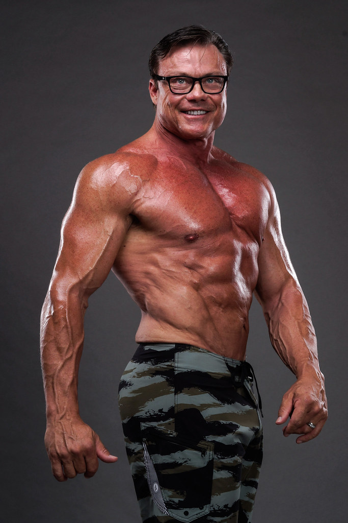 Reagan Lancaster — NPC competitive bodybuilder physique studio portrait, camo shorts